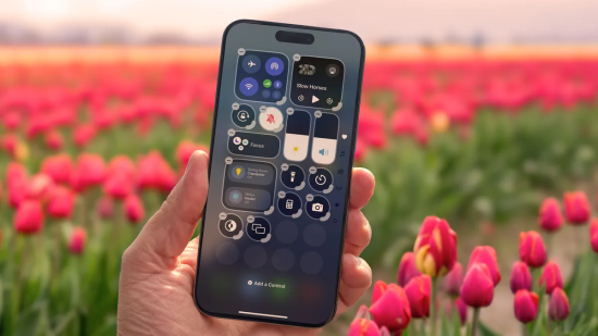 Hand holding iPhone with Control Center open in tulip field.