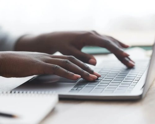 Fingers pressing on a laptop's keyboard.
