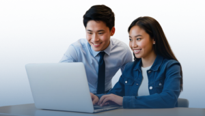 Two students smiling at a laptop.